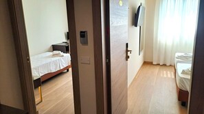 A hotel room with a bed, a bedside table, a TV mounted on the wall, and a window with curtains. - Hotel Internazionale (Cervignano del Friuli)
