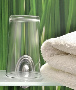 A clear glass container on a glass shelf with a white towel beside it. - centraHOTEL (Schwedt/Oder)