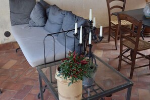 A room with a sofa, a table with a glass top, and a potted plant.