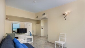 A modern hotel room with a sofa, TV, and a view of the sea. - Riviera (San Vito Lo Capo)