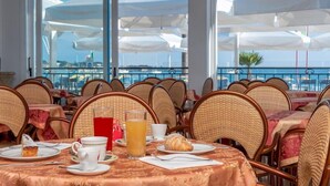 A restaurant with wicker chairs and tables, a glass of juice, a croissant, and a dessert on a plate. - Riviera (San Vito Lo Capo)