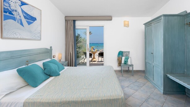 A bedroom with a bed, a view of the beach, a wardrobe, and a painting on the wall. - Riviera (San Vito Lo Capo)