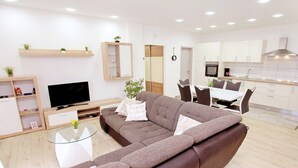 A modern living room with a sectional sofa, a glass coffee table, and a flat-screen TV. - Apartments Jozo (Trogir)