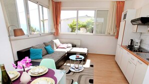 A compact living space with a sofa, dining table, and kitchen area. - Apartments Jozo (Trogir)