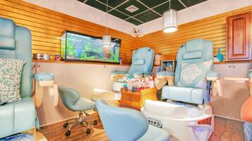 Un espace de bien-être moderne doté de deux fauteuils de massage, d’un grand aquarium et de panneaux muraux en bois.