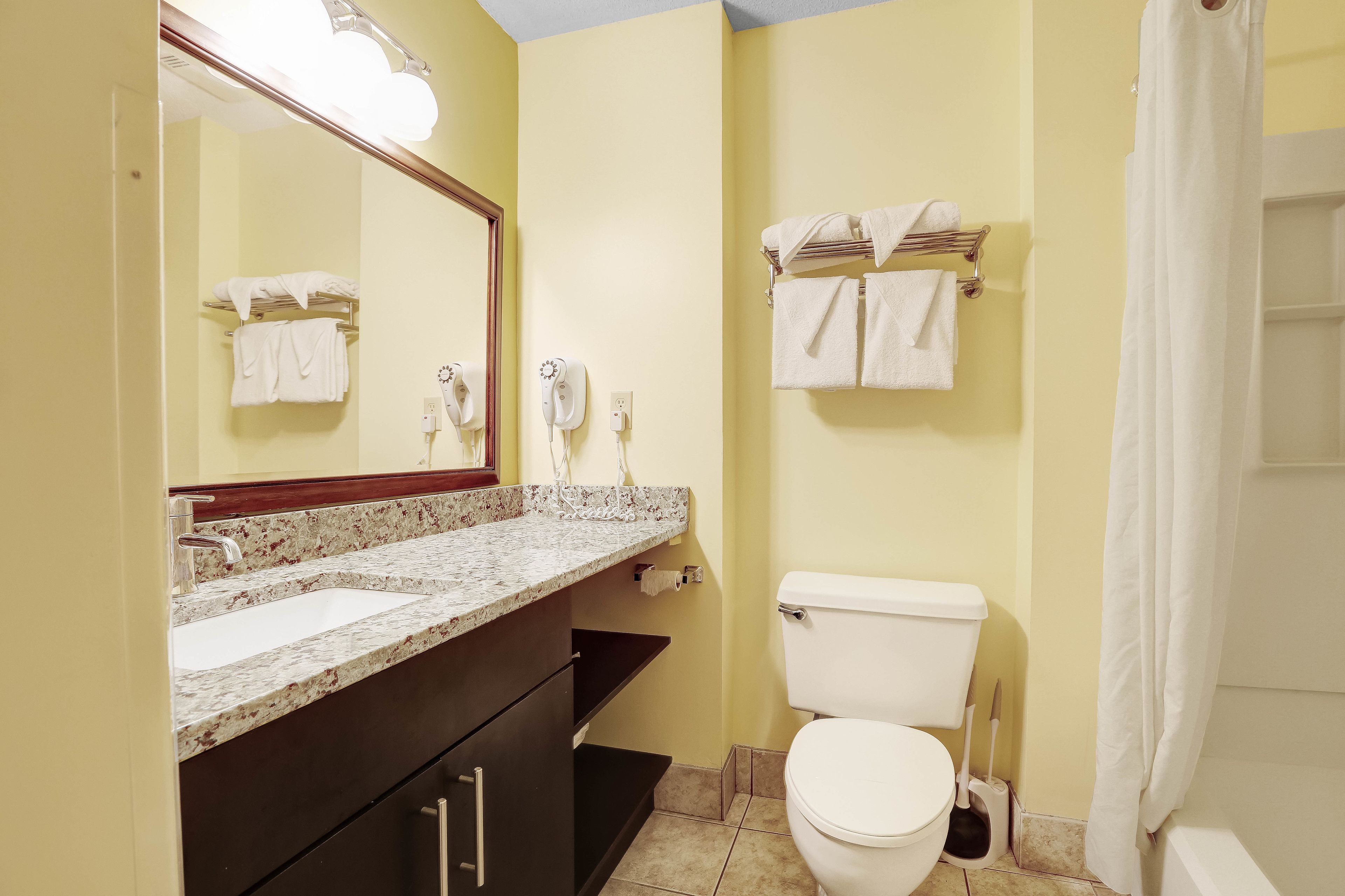 A bathroom with a sink, mirror, toilet, and towel rack.