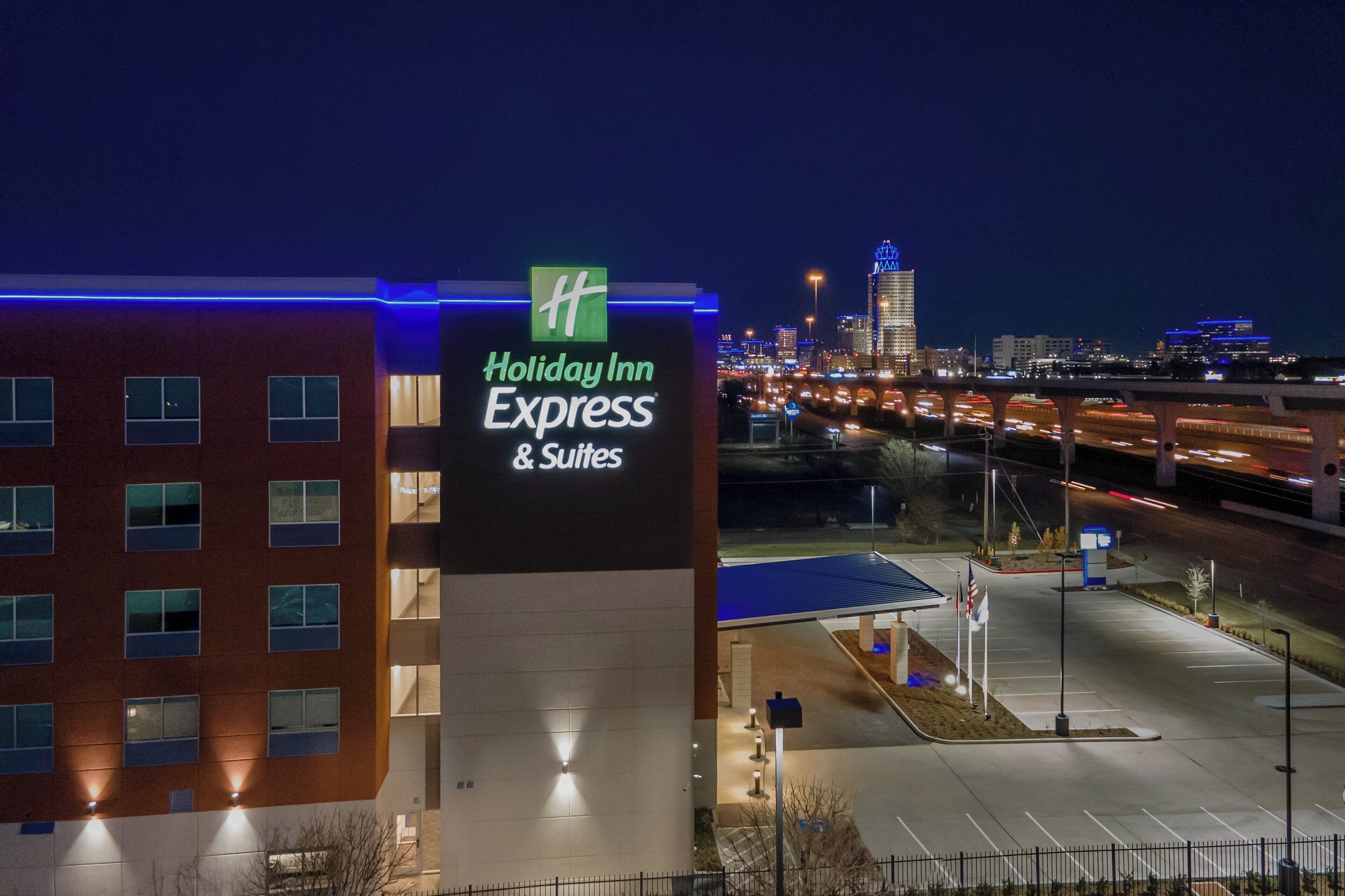 A Holiday Inn Express & Suites sign with a view of a city skyline and a parking lot.