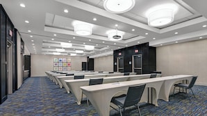 A conference room with rows of tables and chairs, a carpeted floor, and ceiling lights. - Holiday Inn Express & Suites Houston - Memorial City Centre by IHG (Houston)