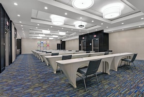 A conference room with rows of tables and chairs, a carpeted floor, and ceiling lights. - Holiday Inn Express & Suites Houston - Memorial City Centre by IHG (Houston)