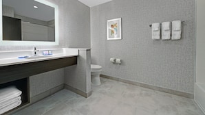 Een moderne badkamer met een grote spiegel, een wastafel, toilet en een handdoekhouder.