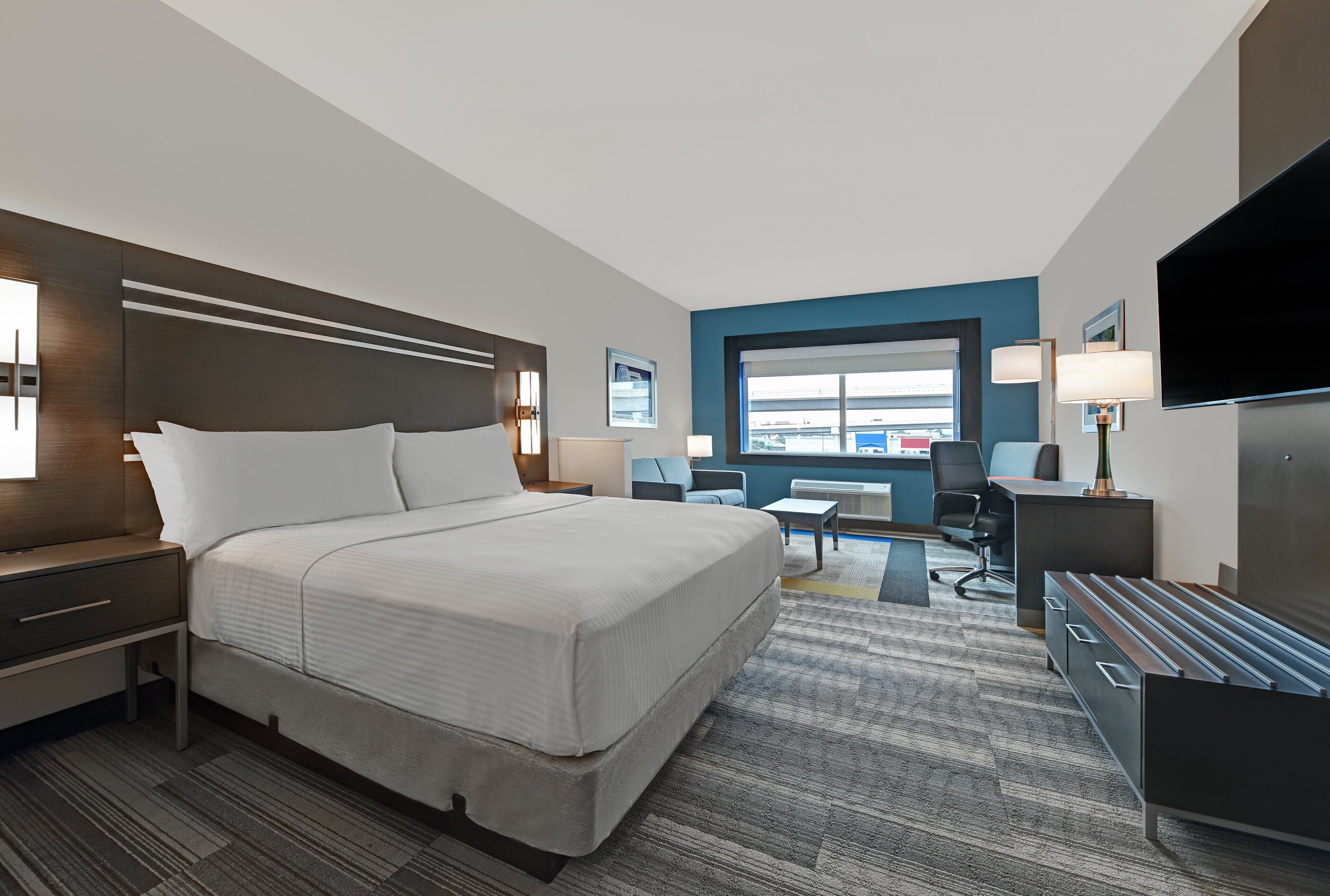 Une chambre d’hôtel moderne équipée d’un grand lit, d’un bureau, d’une chaise et d’un téléviseur.