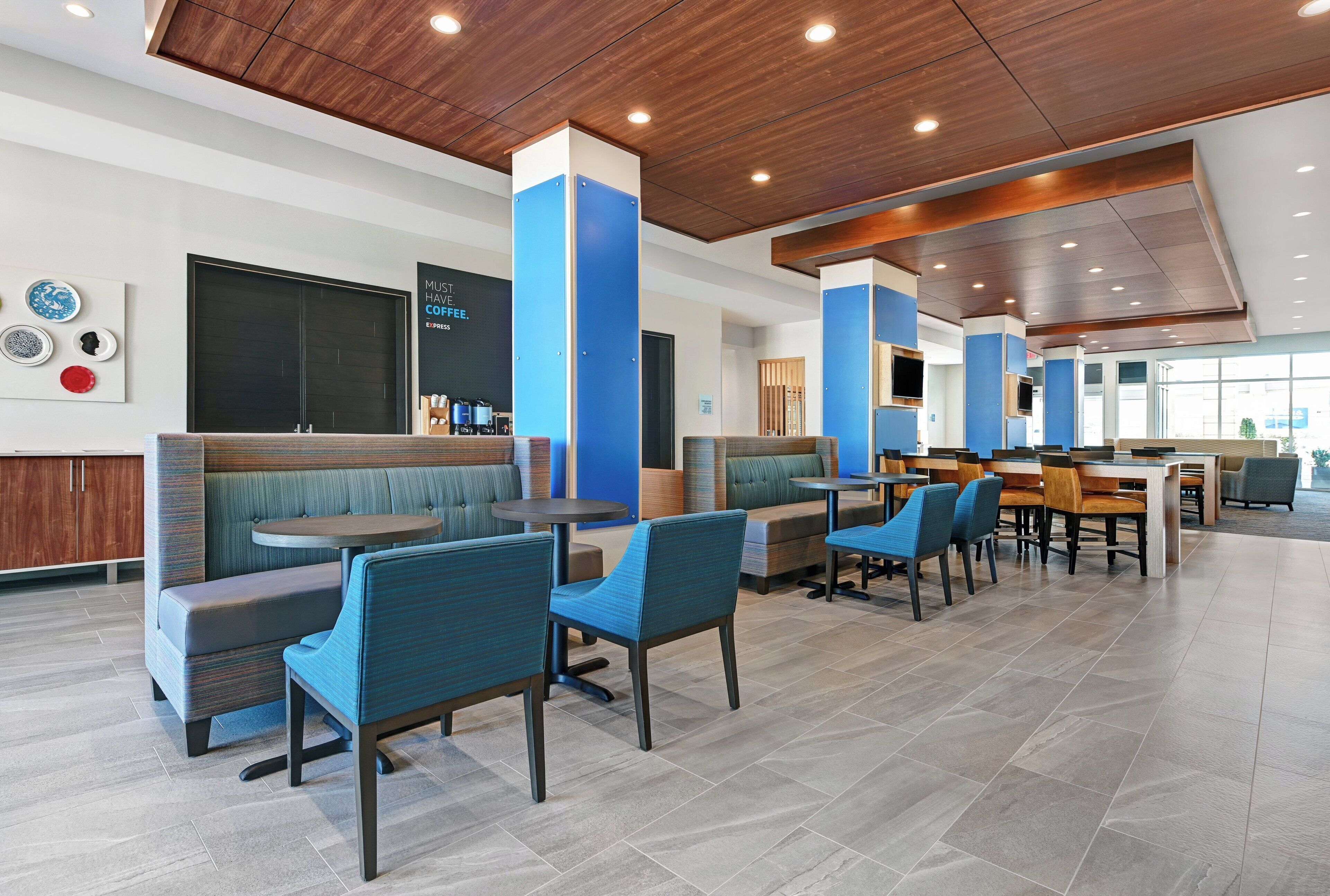 Un restaurante moderno con cabinas y mesas, techo de madera y una pared azul decorativa.
