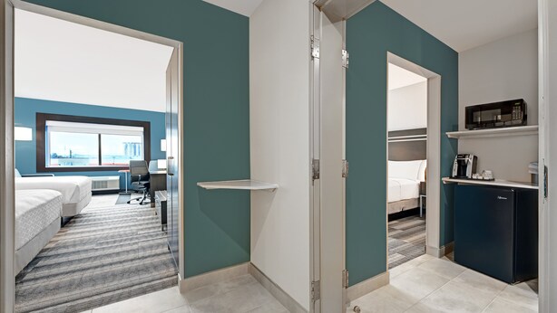 Een hotelkamer met een bed, een bureau, een stoel, een magnetron en een koelkast.