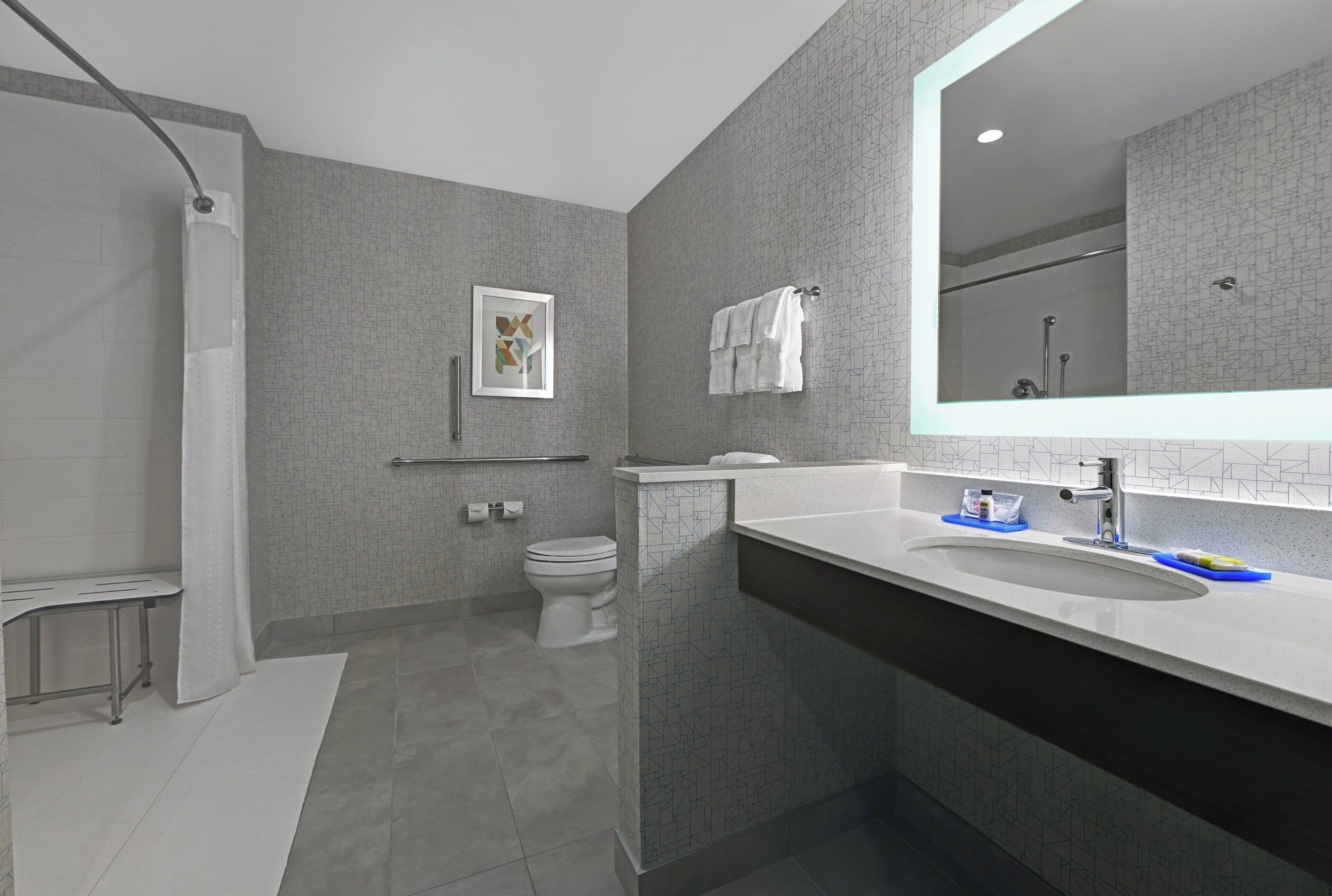 A modern bathroom with a shower, toilet, and sink.