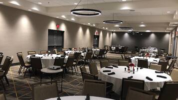 A conference room with round tables, chairs, and a stage area.