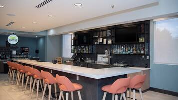 Zona de bar moderna con una barra larga, taburetes y una variedad de botellas de licor.
