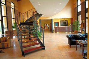 A spacious lobby with a central staircase, seating area, and a reception desk.