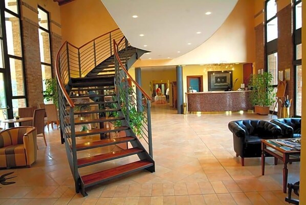 A spacious lobby with a central staircase, seating area, and a reception desk.