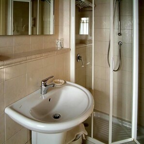 A bathroom with a white sink, a mirror, and a glass-enclosed shower.
