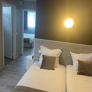 A hotel room with a bed, bedside table, and a wall-mounted light fixture. - Contact Hôtel Foch (Besancon)
