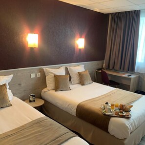 A hotel room with two beds, a desk, and a chair. There is a tray of breakfast items on the bed. - Contact Hôtel Foch (Besancon)