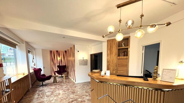 Un'area reception con pavimento in pietra, scrivania in legno e un lampadario moderno.