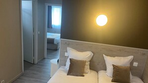 Camera d'albergo con un letto matrimoniale, due cuscini, un comodino e una lampada fissata al muro.