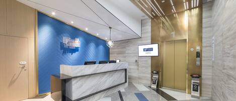 A modern reception area with a marble counter, blue and beige walls, and an elevator.