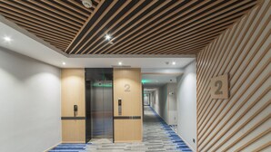 Un pasillo moderno de hotel con techo de madera, alfombra estampada y un letrero con el número 2 en la pared.