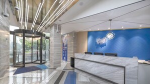 A modern hotel lobby with a marble reception desk, a blue chevron-patterned wall, and a revolving door. - Holiday Inn Express Shanghai Gubei by IHG (Shanghai)