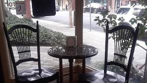 A corner seating area with two chairs and a small round table, a window with a view of the street, and a sign for a garden inn. - Los Gatos Garden Inn Hotel (Los Gatos)