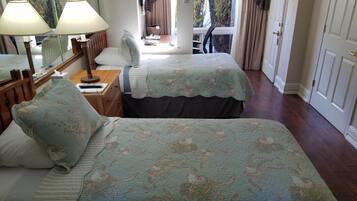 Habitació d'hotel amb dos llits, un escriptori amb una làmpada, una cadira i una finestra amb cortines.
