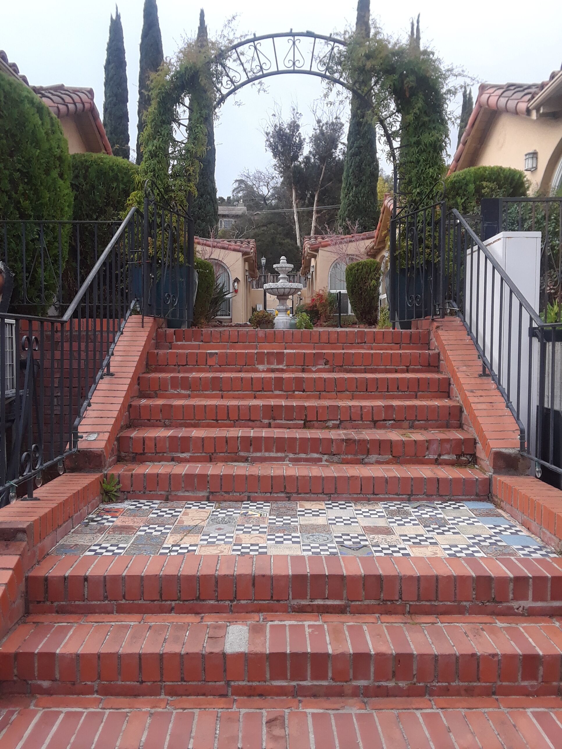 A set of brick stairs leading up to a gated entrance with a decorative archway.