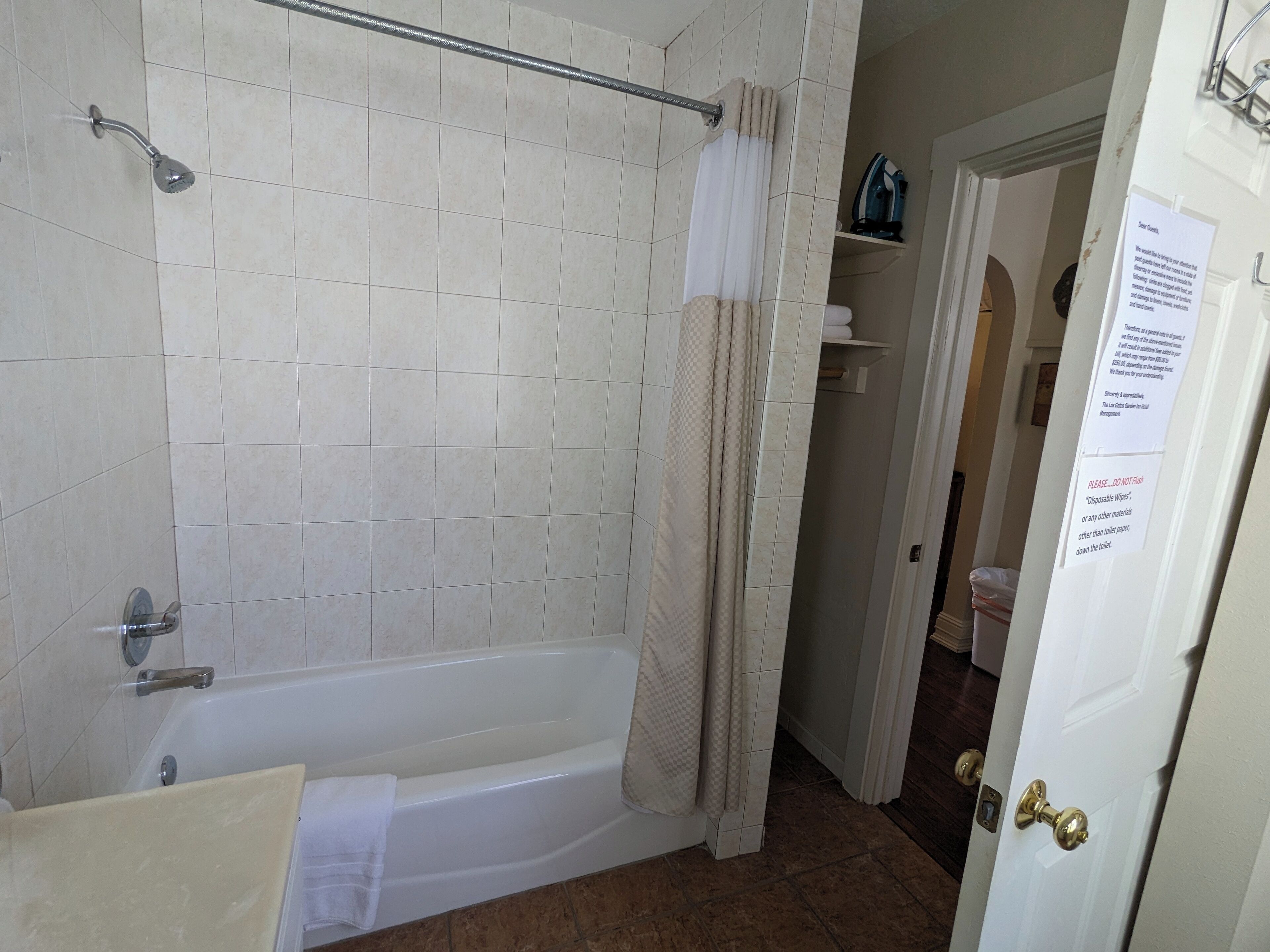 A bathroom with a bathtub, a shower, and a toilet. There is a towel hanging on the bathtub.