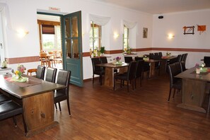 A restaurant with wooden tables and chairs, a blue door, and a white wall with a red stripe.