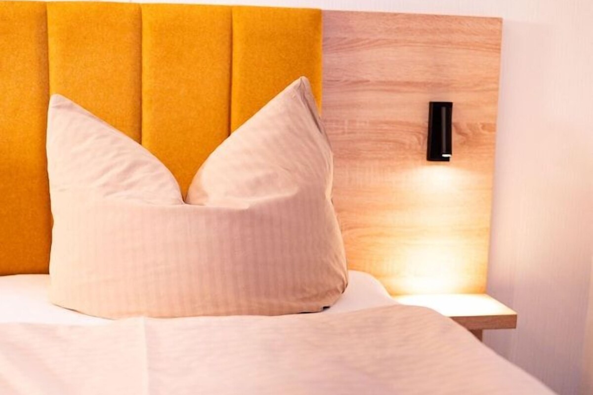 Ein ordentlich bezogenes Bett mit Kopfteil, Kissen und Decke.