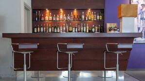 Eine Bar mit drei Hockern und einem Regal voller Spirituosen.