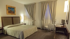 Ein Hotelzimmer mit Bett, Schreibtisch, Stuhl, Lampe und einem Bild an der Wand.