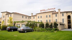 Ein Hotel mit einem Schild, auf dem 'HOTEL del GONZAGA' steht. Vor dem Hotel sind zwei Autos geparkt.