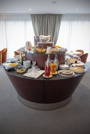 A breakfast buffet setup with various food items and beverages on a round table. - Hotel dei Gonzaga (Reggiolo)