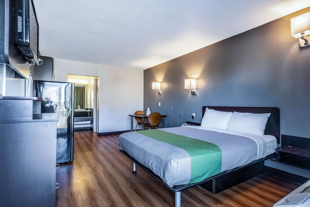 Une chambre d’hôtel moderne équipée d’un lit, d’un bureau, d’une chaise et d’une kitchenette.