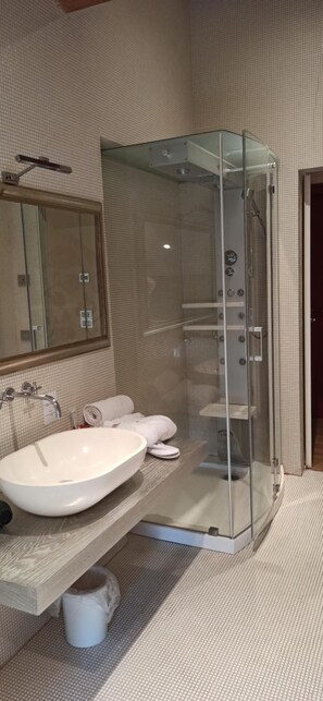 Une salle de bain moderne avec une douche en verre, un grand lavabo blanc et un miroir au-dessus du lavabo.