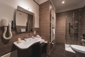 Een moderne badkamer met een ruime wastafel, spiegel en een douchecabine met glazen wanden.