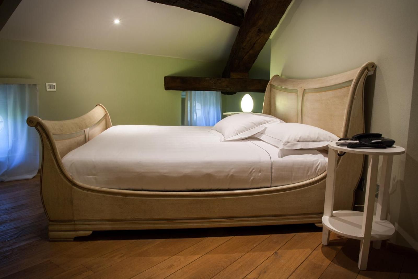 A bed with a headboard, a bedside table with a phone, and a window with curtains.