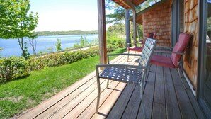 A wooden deck with a bench and chairs overlooking a lake. - Whaleback Inn (Leland)