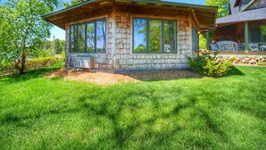 A wooden cabin with large windows, a covered porch, and a stone foundation. - Whaleback Inn (Leland)