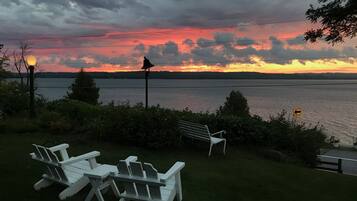 Relax in a serene lakeside setting with a peaceful outdoor seating area featuring Adirondack chairs and a bench.