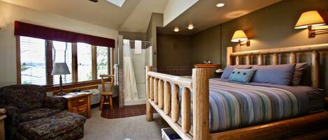 A bedroom with a skylight, a wooden bed, a chair, a desk, and a bathroom with a shower.