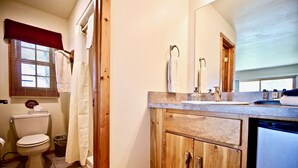 A bathroom with a toilet, sink, and wooden cabinets.