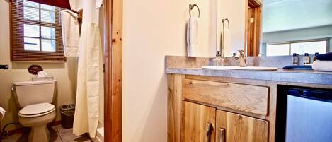 A bathroom with a toilet, sink, and wooden cabinets.